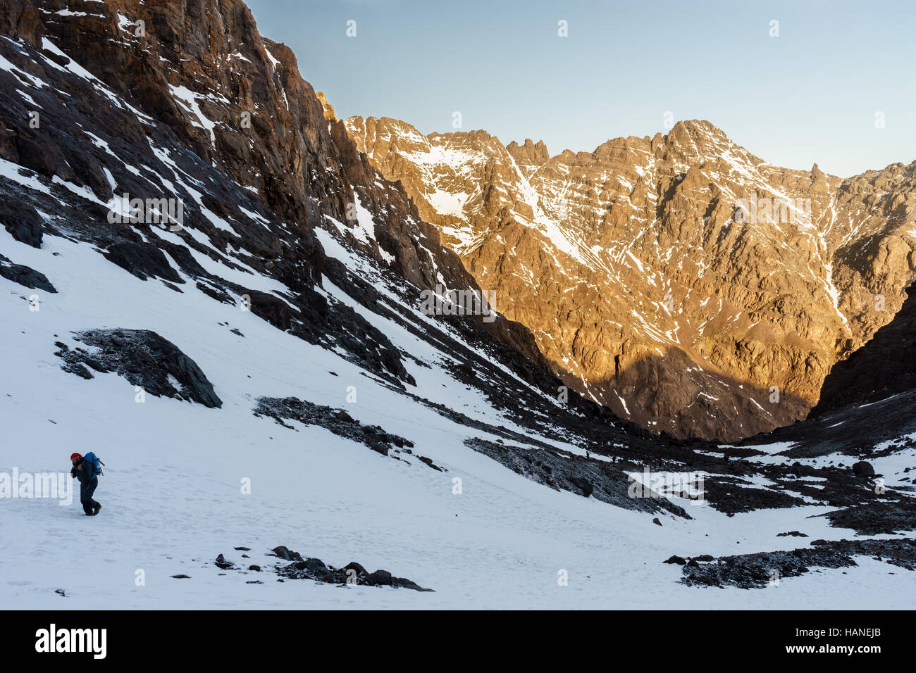 Ein kaukasischer Bergsteiger Mann geht durch den Schnee auf den Gipfel des Jbel Toubkal bei Sonnenaufgang Stockfoto