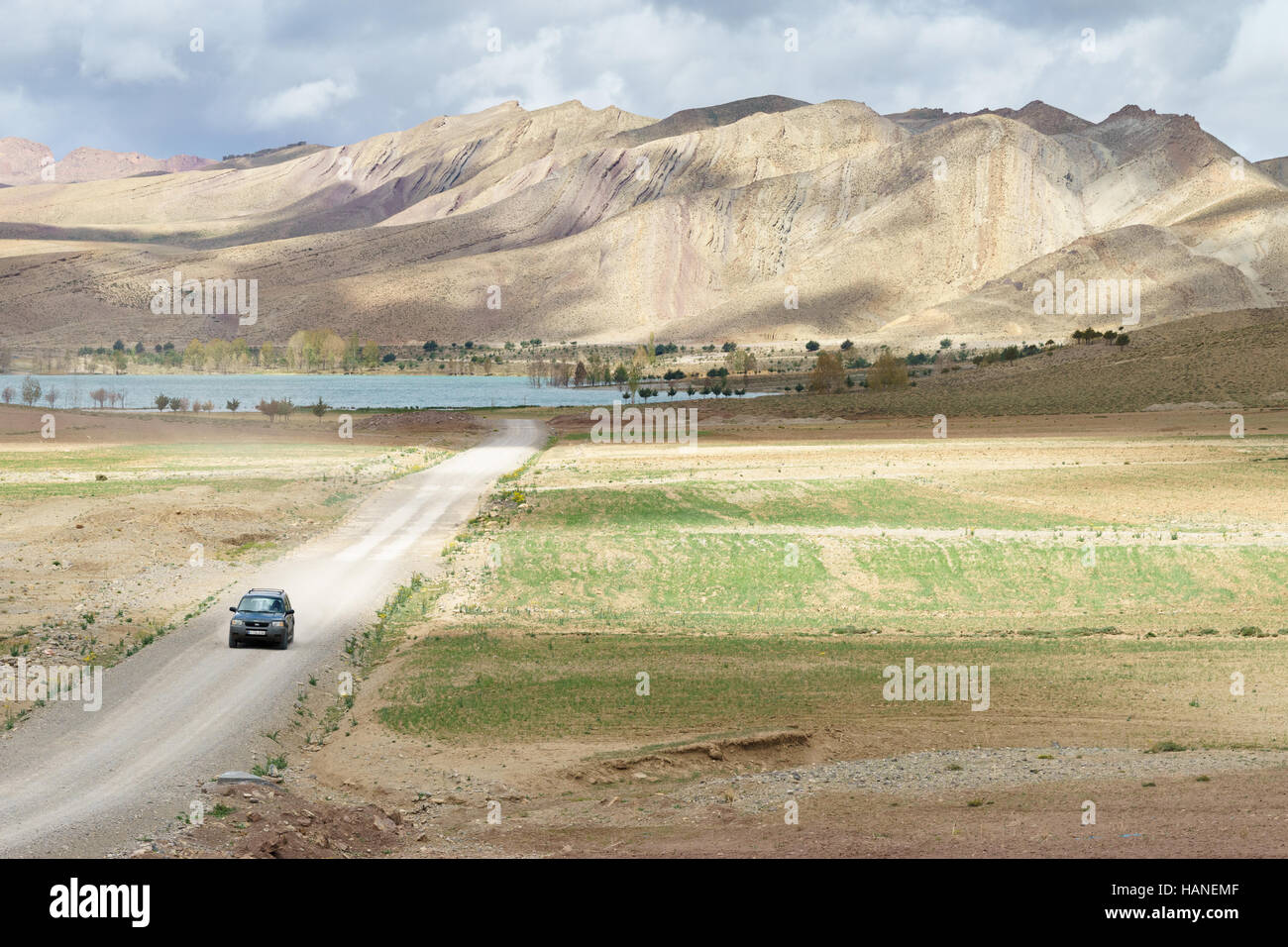 Ein Offroad-Fahrzeug bewegt sich entlang einer unbefestigten Straße hinter Tislit See und die Berge des marokkanischen atlas Stockfoto