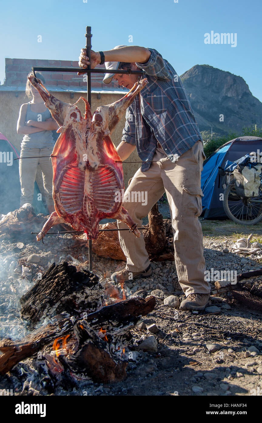 Ein argentinischer Mann bereitet einen Lammbraten für eine Feier Stockfoto
