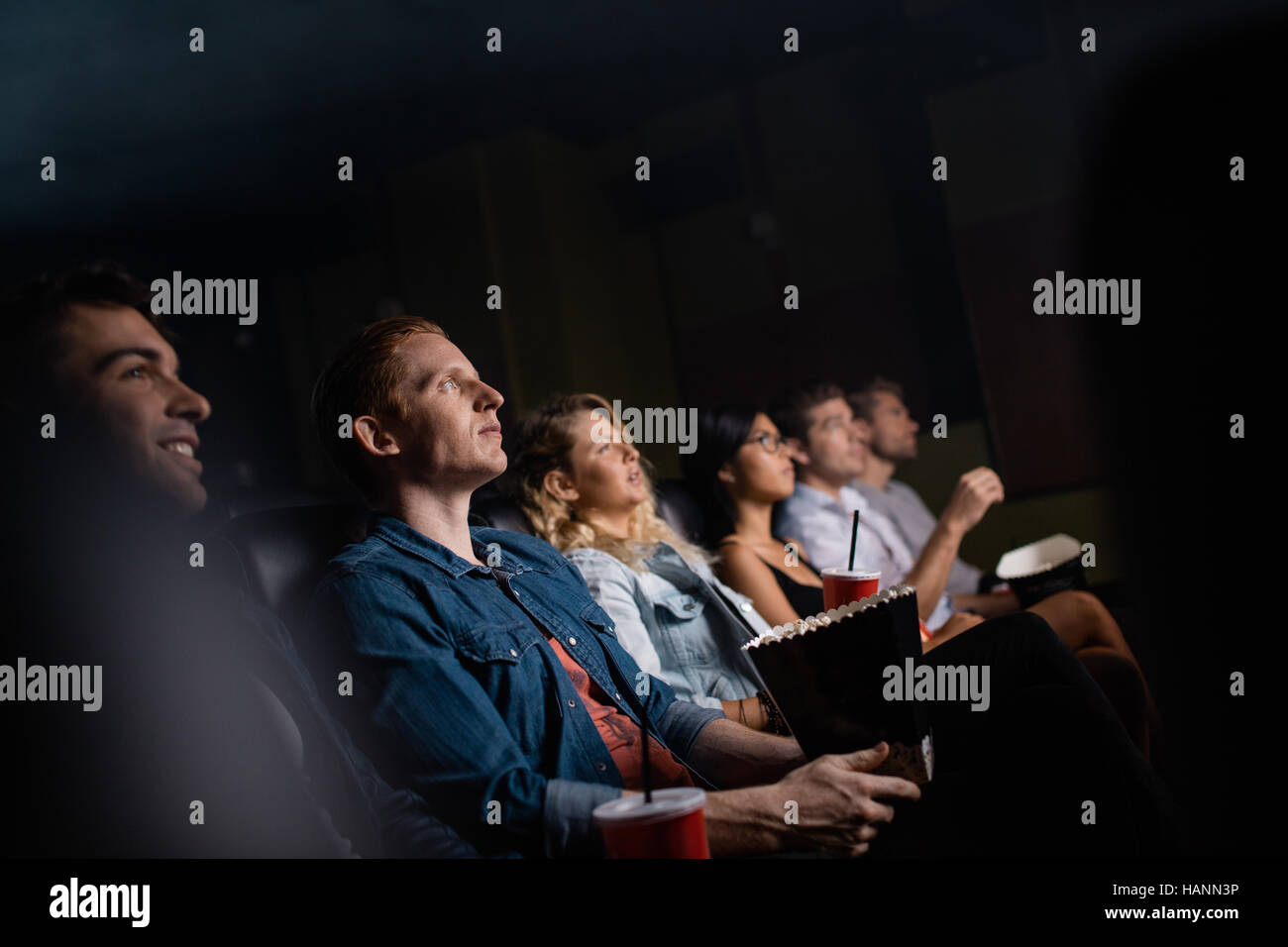 Junger Mann mit Freunden im Kinosaal Film. Gruppe von Menschen Film im Theater. Stockfoto