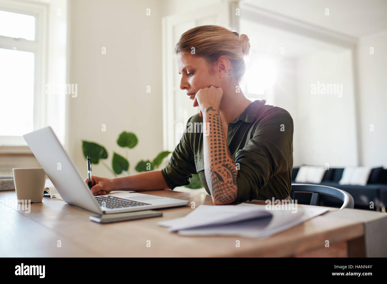 Schuss von junge Frau Büro zu Hause arbeiten. Schöne Frau mit Laptop und Dokumente am Tisch sitzen. Stockfoto