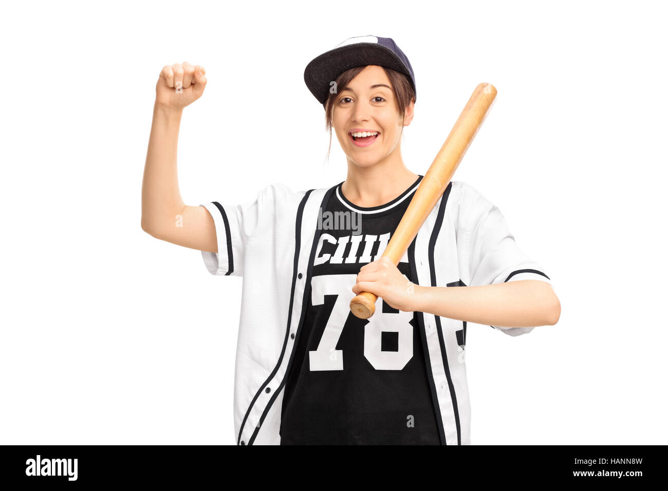 Fröhliches Mädchen in einem Baseball Trikot hält eine Fledermaus und deutete mit der Hand isoliert auf weißem Hintergrund Stockfoto