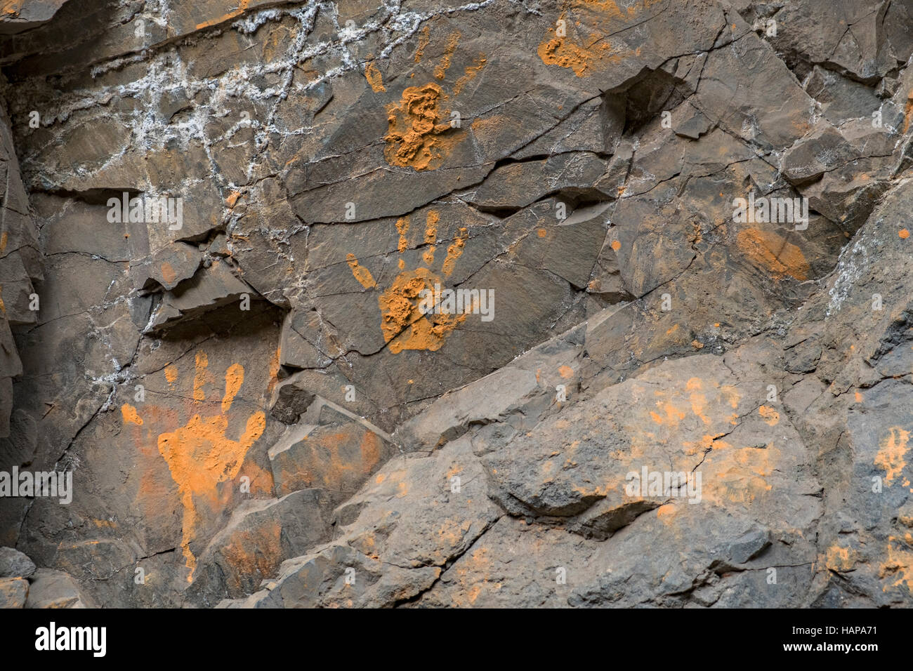 Schlammigen orange Hand druckt auf einer gerissenen Steinmauer Stockfoto