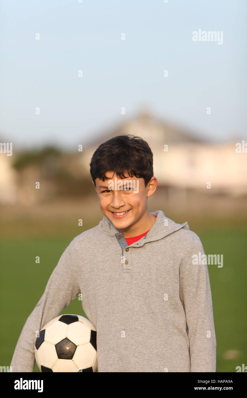 Junge mit Fußball außerhalb der goldenen Stunde bei Sonnenuntergang Stockfoto
