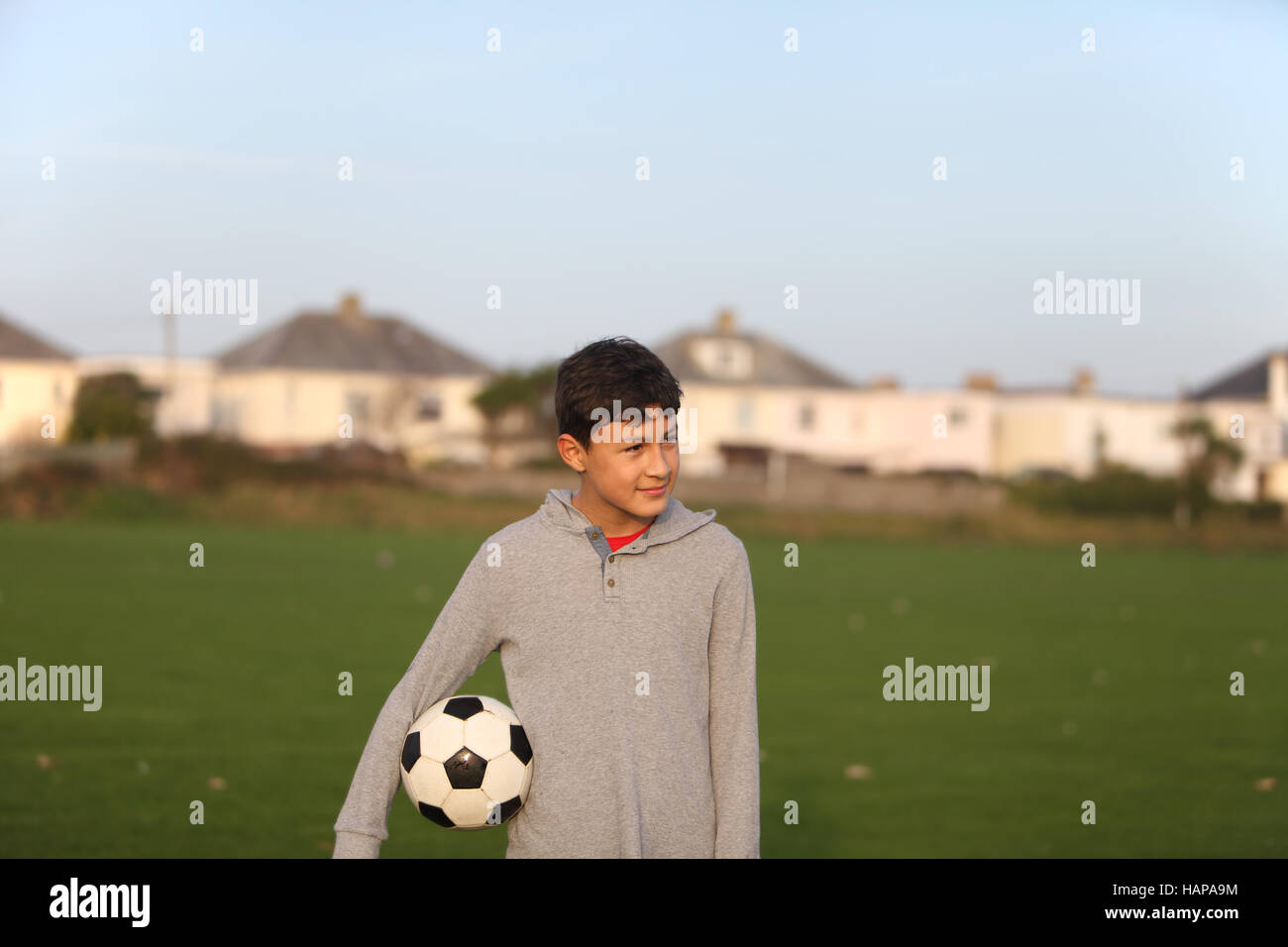 Junge mit Fußball außerhalb der goldenen Stunde bei Sonnenuntergang Stockfoto