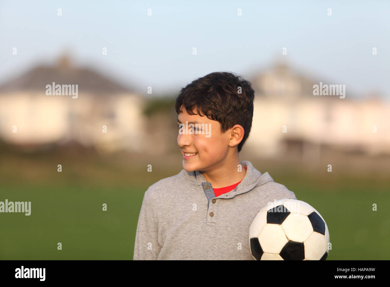 Junge mit Fußball außerhalb der goldenen Stunde bei Sonnenuntergang Stockfoto