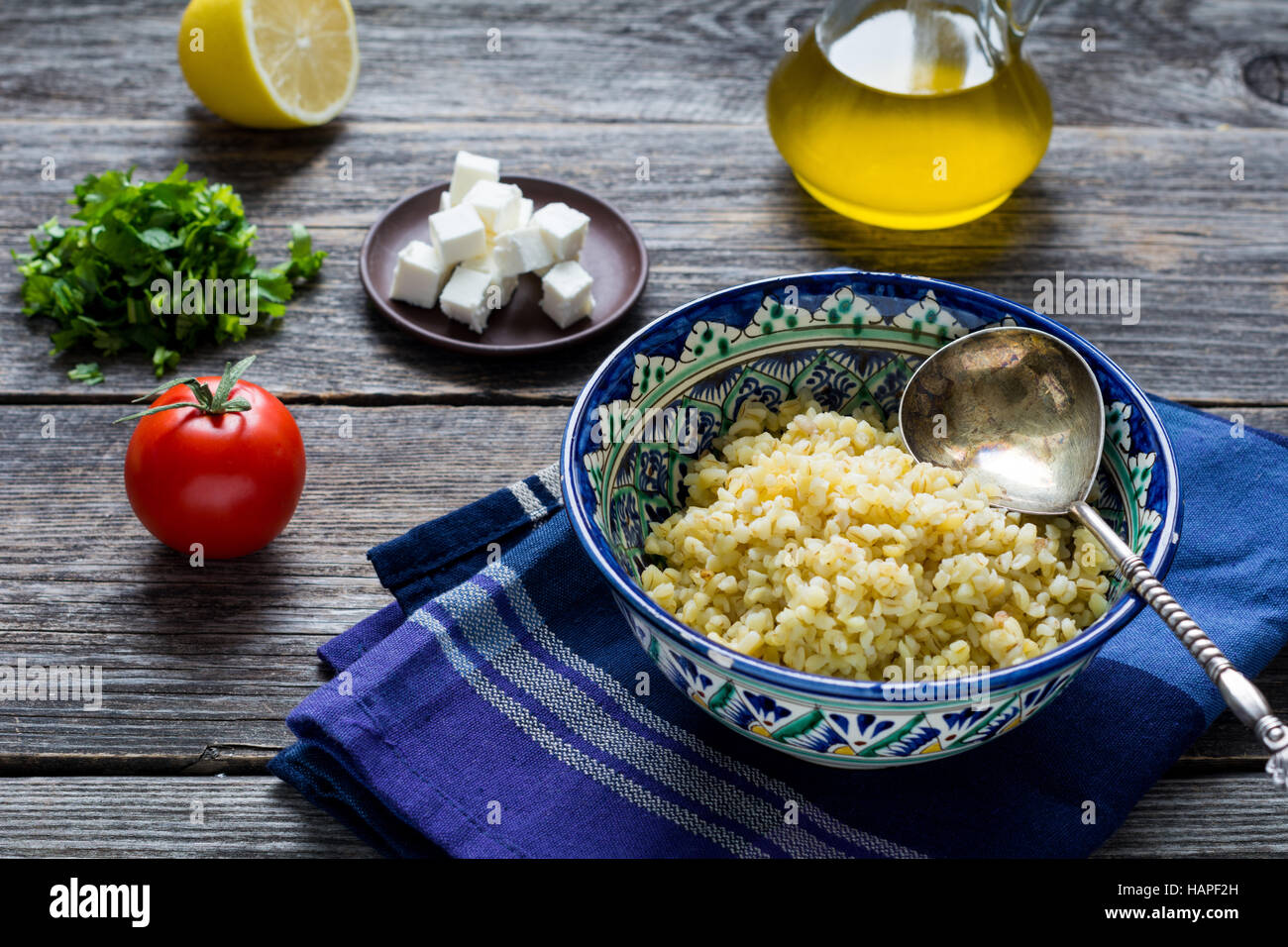 Zutaten für das Kochen Taboulé Salat mit Bulgur, Tomaten, Petersilie, Zitrone, Olivenöl und frischem Ziegenkäse Käse auf hölzernen Tisch bac Stockfoto