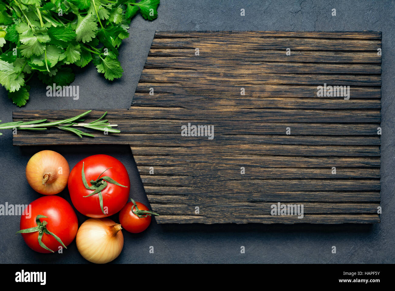 Essen-Hintergrund: Holzbrett, frische Tomaten, Zwiebeln und Bund Petersilie. Leeren Raum für Ihren Text. Ansicht von oben Stockfoto
