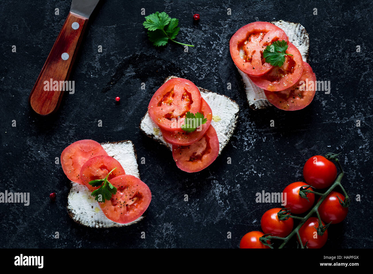 Ziegenkäse und Tomate snack Sandwiches auf dunklen Schiefer Tisch Hintergrund. Ansicht von oben. Gesunde Ernährung Stockfoto