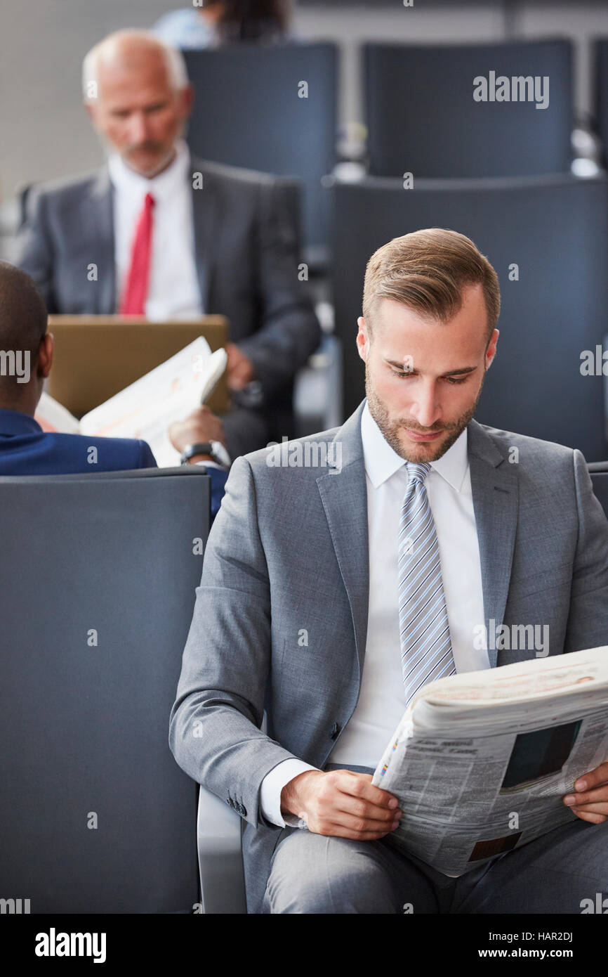 Geschäftsmann, lesen Zeitung warten im Abflugbereich des Flughafen Stockfoto