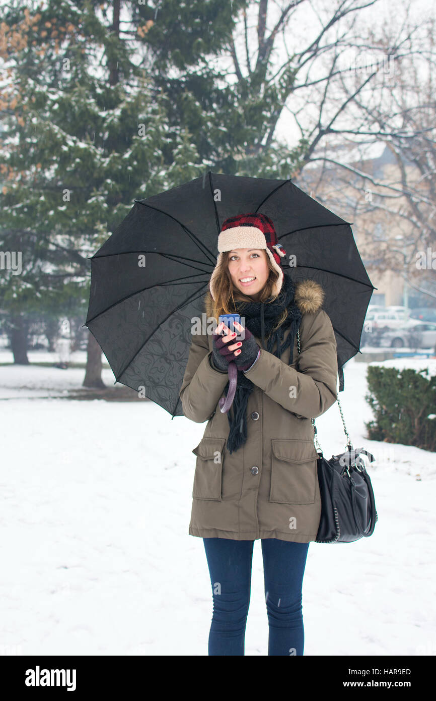 Frau schreiben SMS im tief verschneiten park Stockfoto