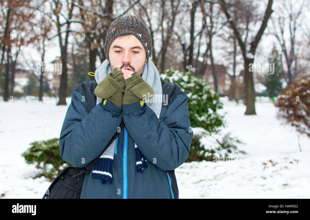 Junger Mann Aufwärmen Hände im tief verschneiten park Stockfoto