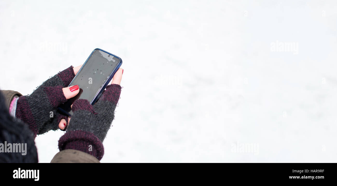 Weibliche Hände in Handschuhe mit einem Smartphone in der Winterzeit Stockfoto
