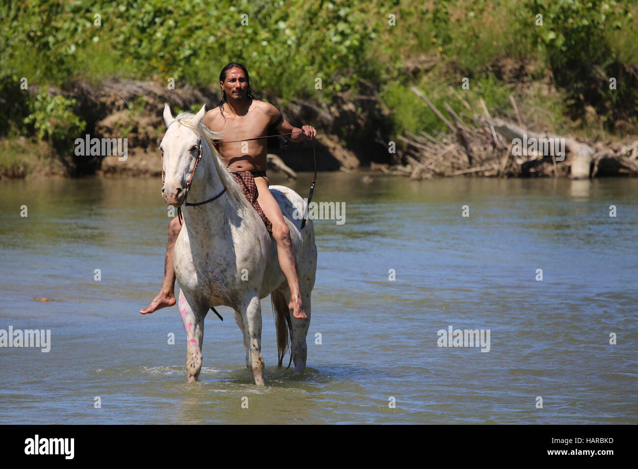 Native American Indian auf dem Pferderücken in Fluss Stockfoto