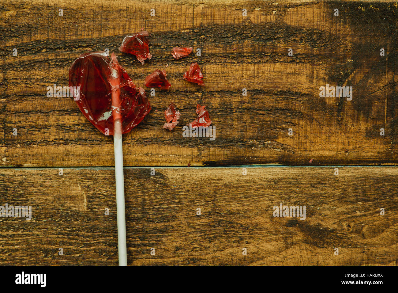 Rote Lollipo mit Herzform auf einem hölzernen Hintergrund gebrochen Stockfoto