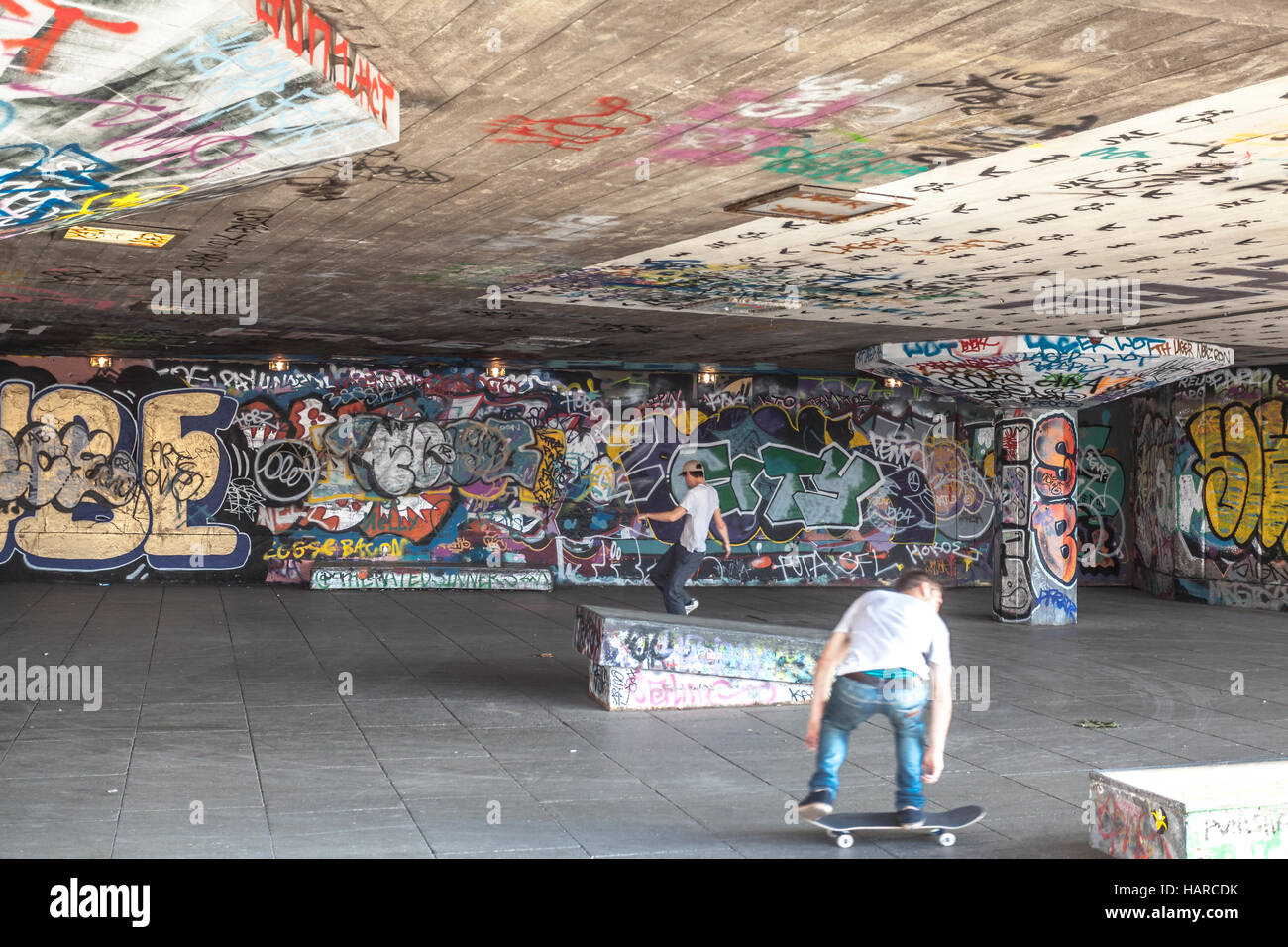 London Boys Skate Skateboardtricks auf Spielplatz mit graffiti Stockfoto