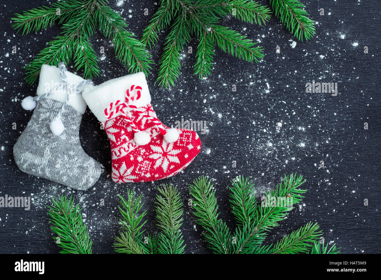 Weihnachten und Neujahr Winter Urlaub snowbound Zusammensetzung von grauen und roten Strümpfen auf schwarzen Raum Hintergrund mit grünen Tannenzweigen Baum Stockfoto