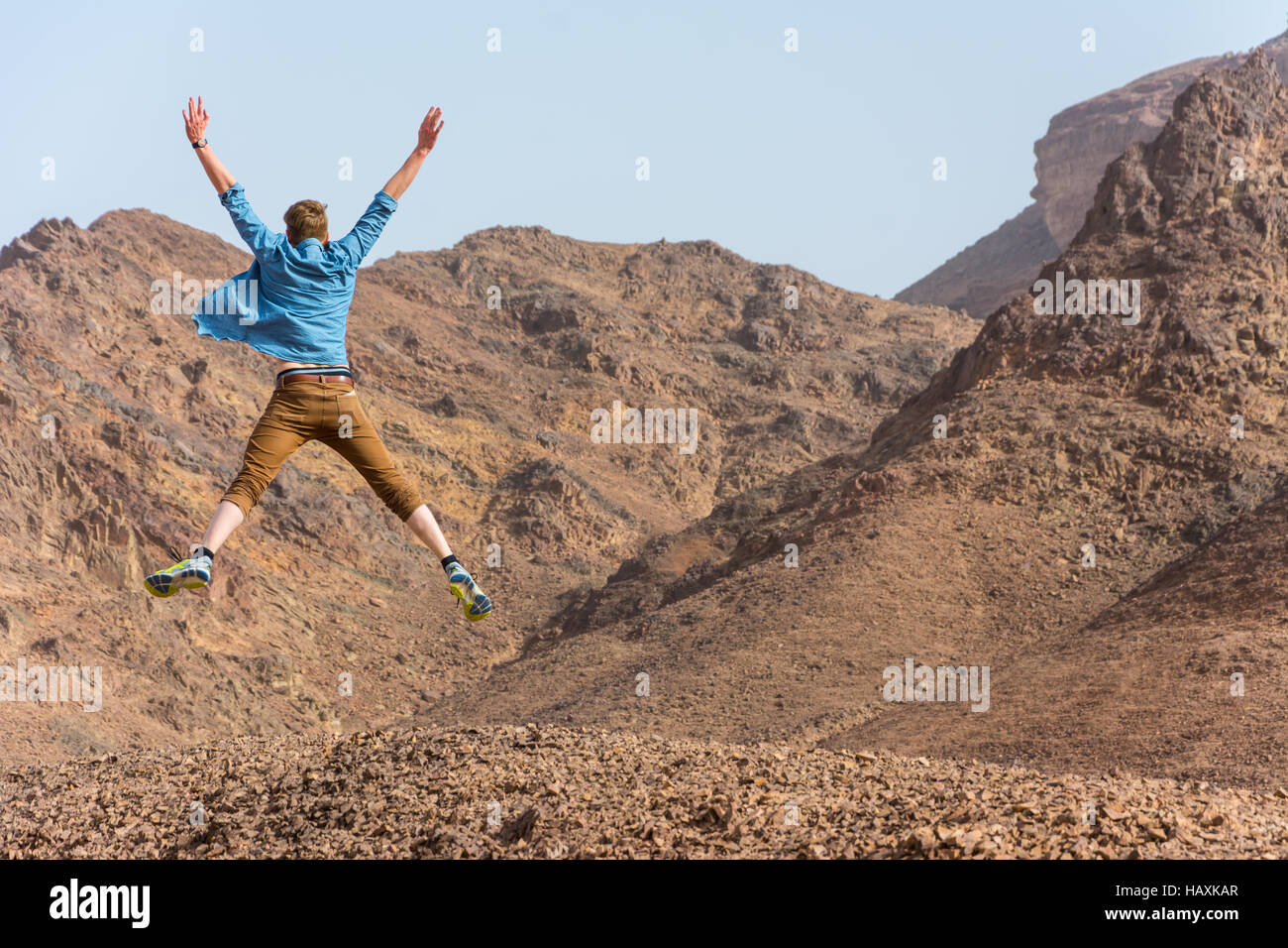 Glücklicher junger Mann springt in der Wüste Stockfoto