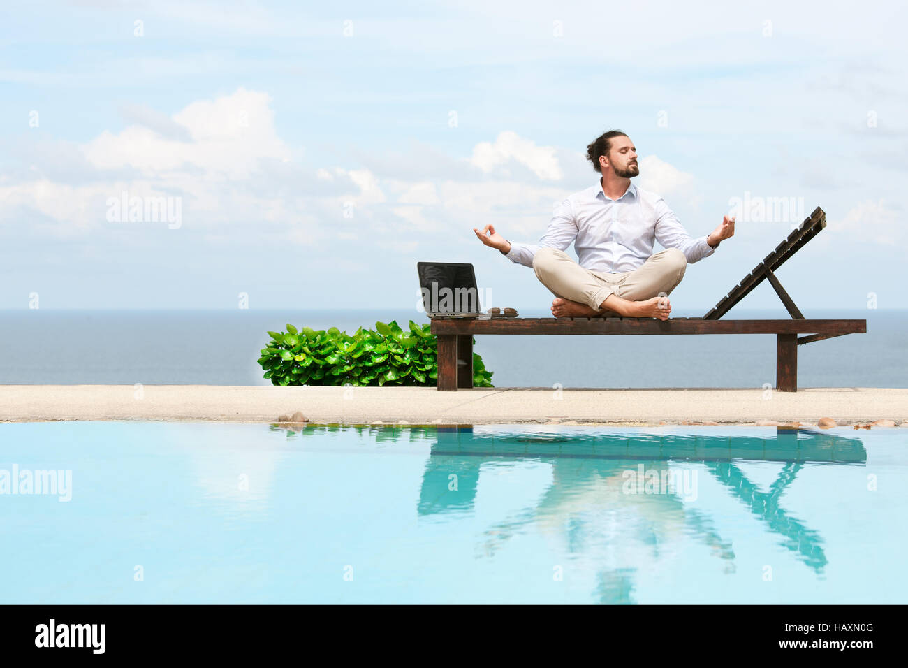 Geschäftsmann in einem Anzug auf Liegestuhl tun Yoga am Strand Stockfoto