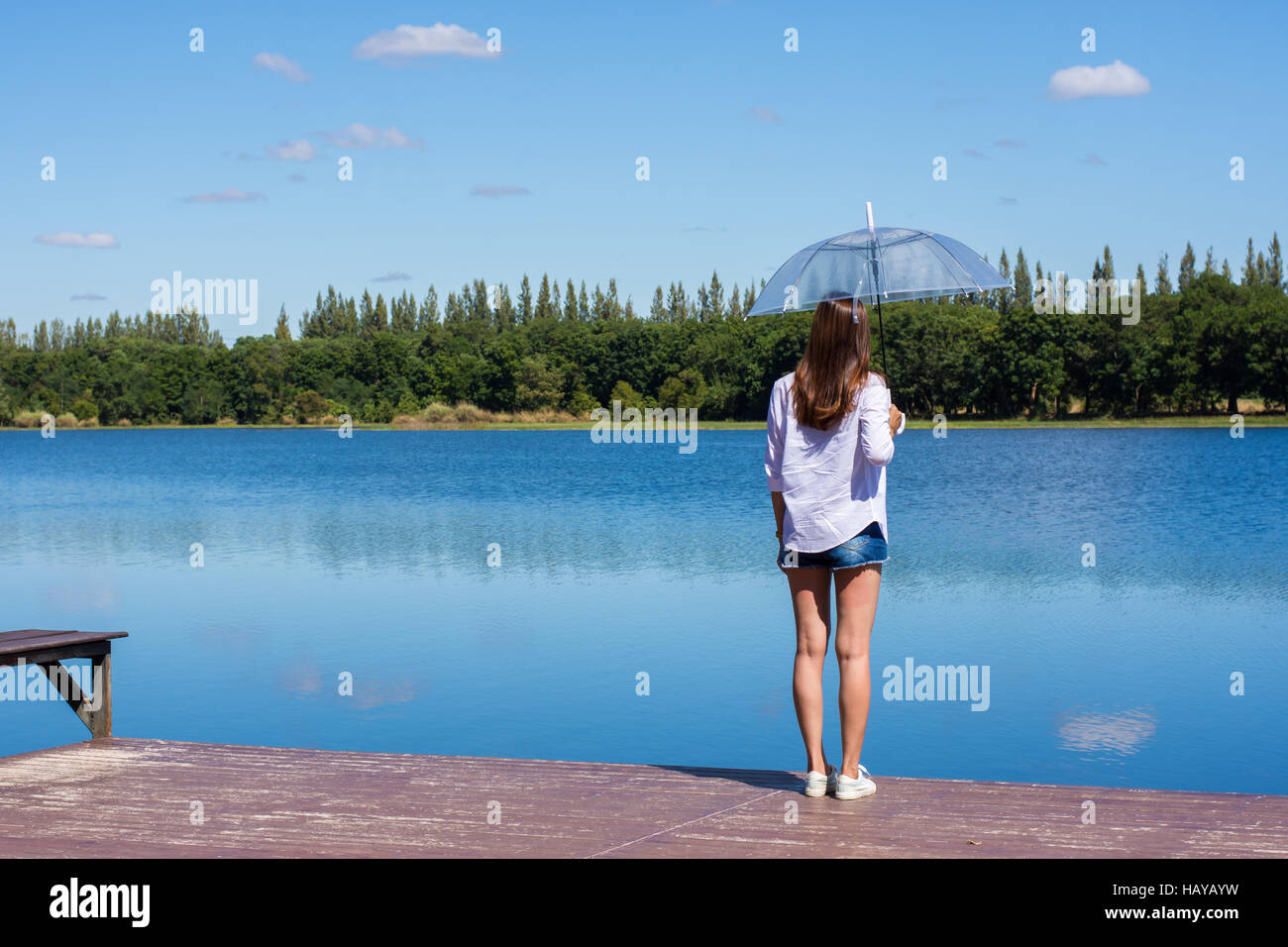 Frau mit Regenschirm stehen, einen Teich und Natur beobachten. Stockfoto