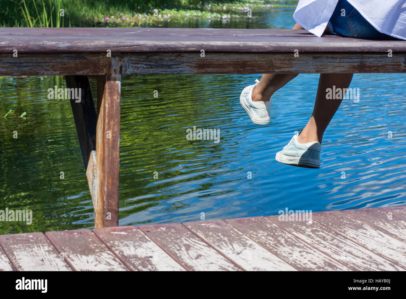 Frauenfüße über den Swimmingpool im Garten. Stockfoto