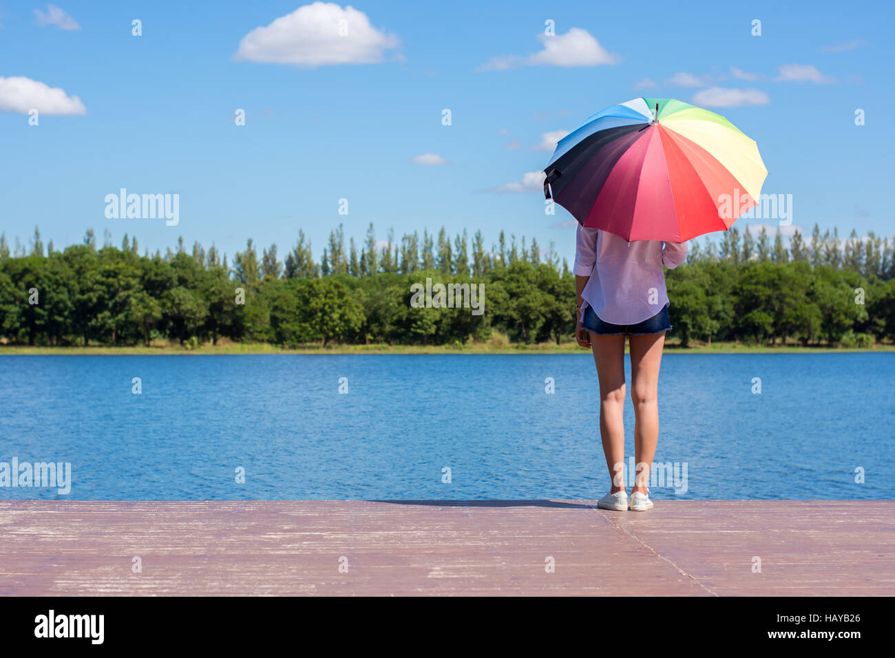 Frau mit Regenschirm stehen, einen Teich und Natur beobachten. Stockfoto