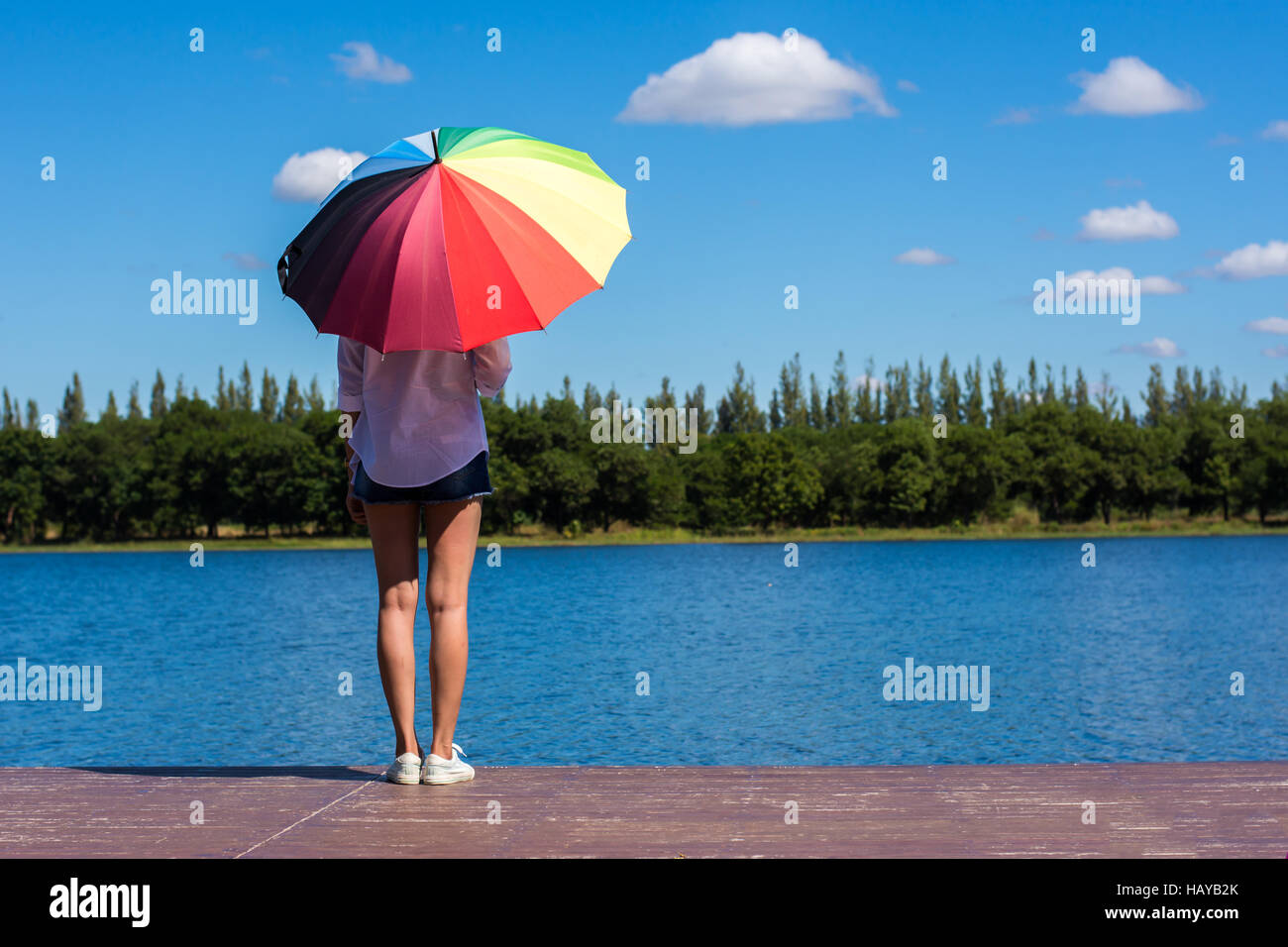 Frau mit Regenschirm stehen, einen Teich und Natur beobachten. Stockfoto