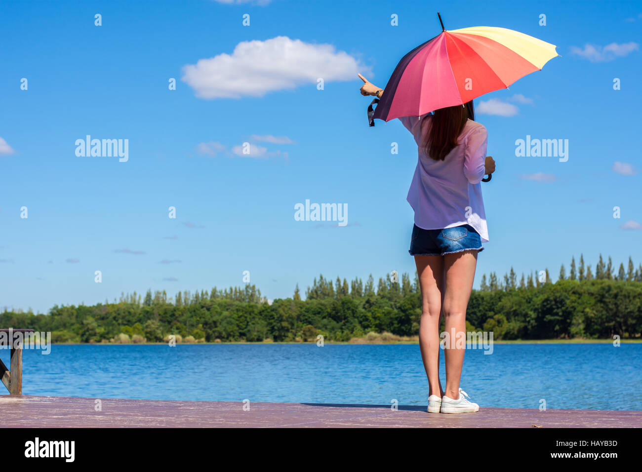 Frau mit Regenschirm stehen, einen Teich und Natur beobachten. Stockfoto