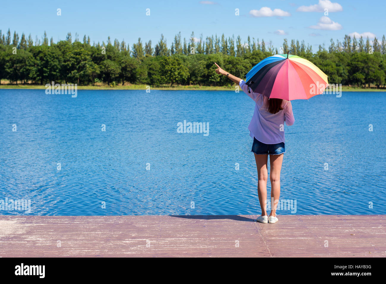 Frau mit Regenschirm stehen, einen Teich und Natur beobachten. Stockfoto