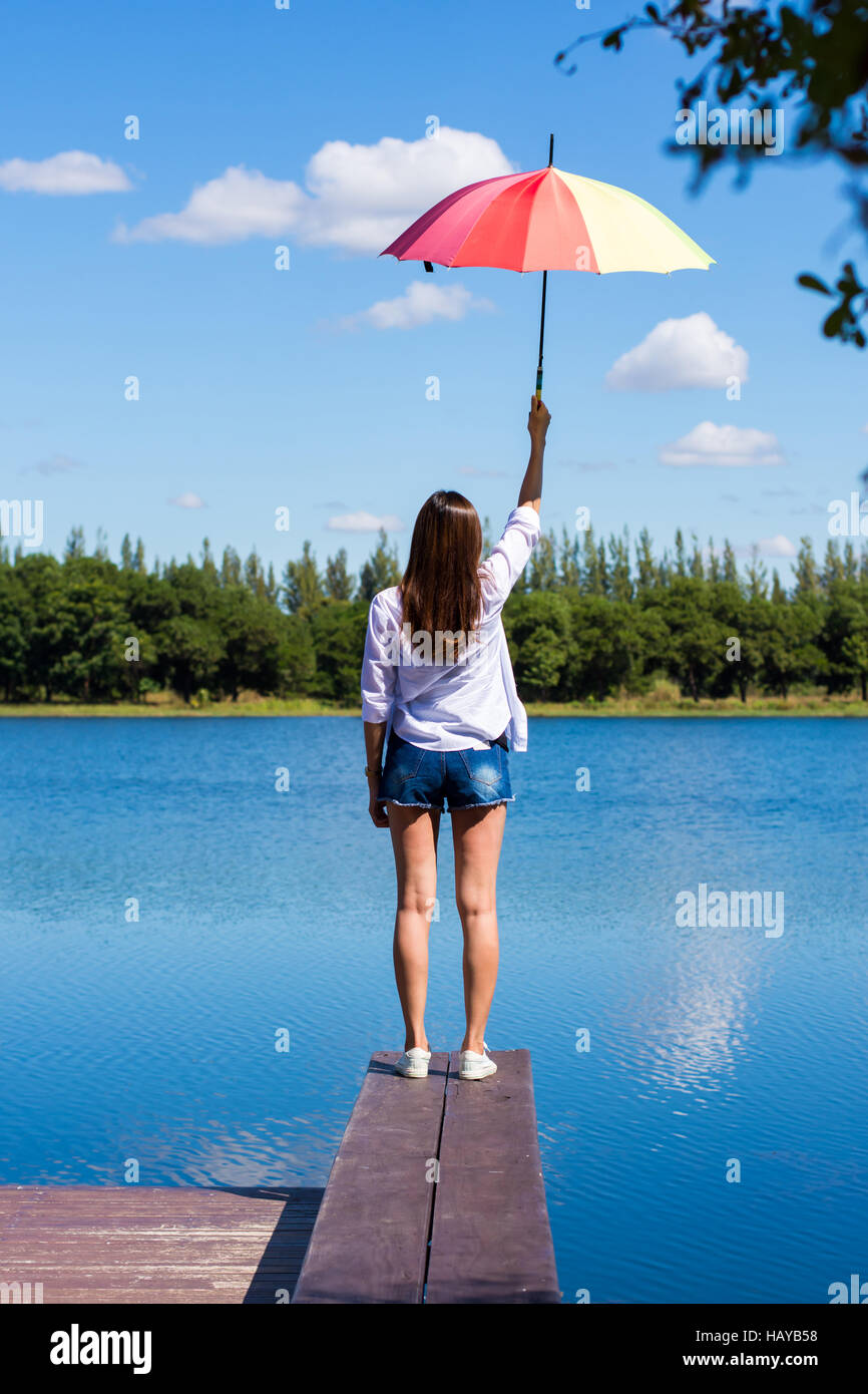 Frau mit Regenschirm stehen, einen Teich und Natur beobachten. Stockfoto