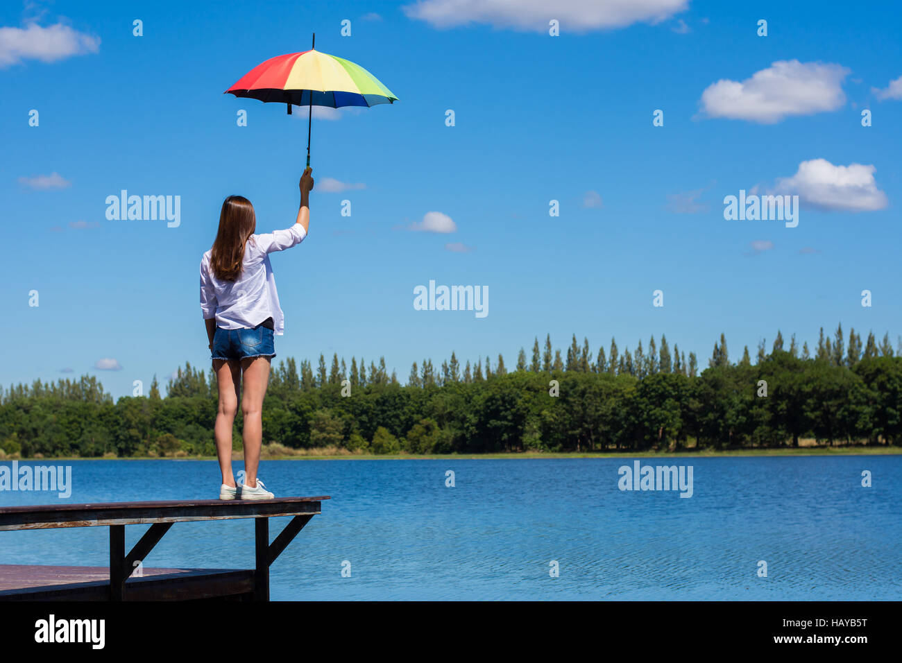 Frau mit Regenschirm stehen, einen Teich und Natur beobachten. Stockfoto