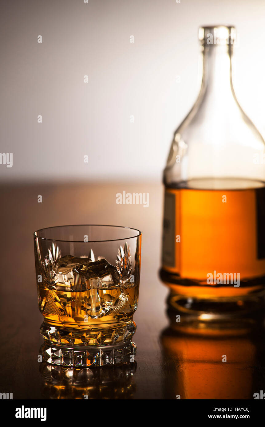 Whisky mit Eis im Glas und Flasche auf hölzernen Hintergrund Stockfoto
