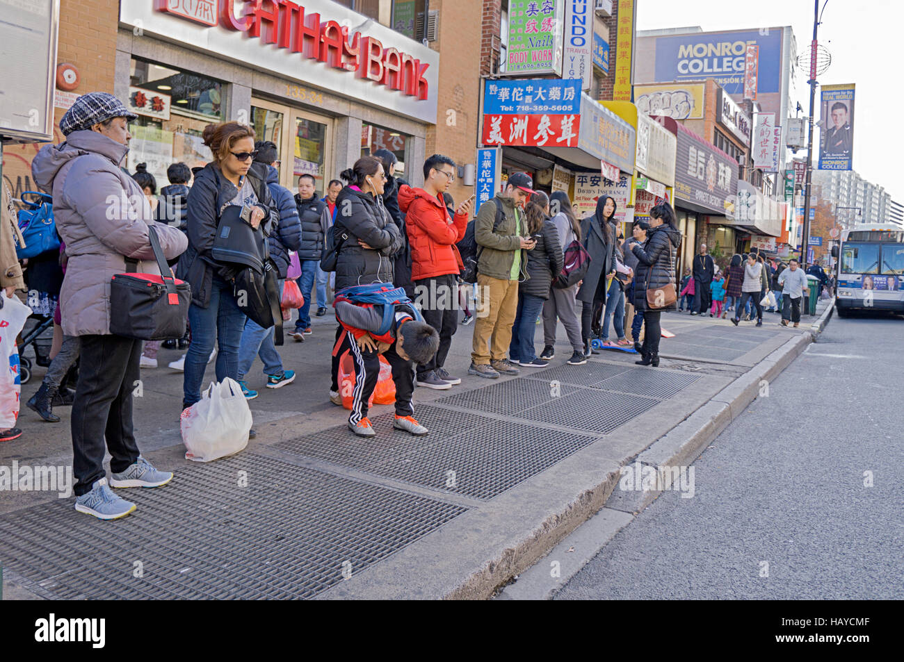 Eine lange Schlange von Menschen warten auf einen Bus in Chinatown, Downtown Flushing, New York City. Stockfoto