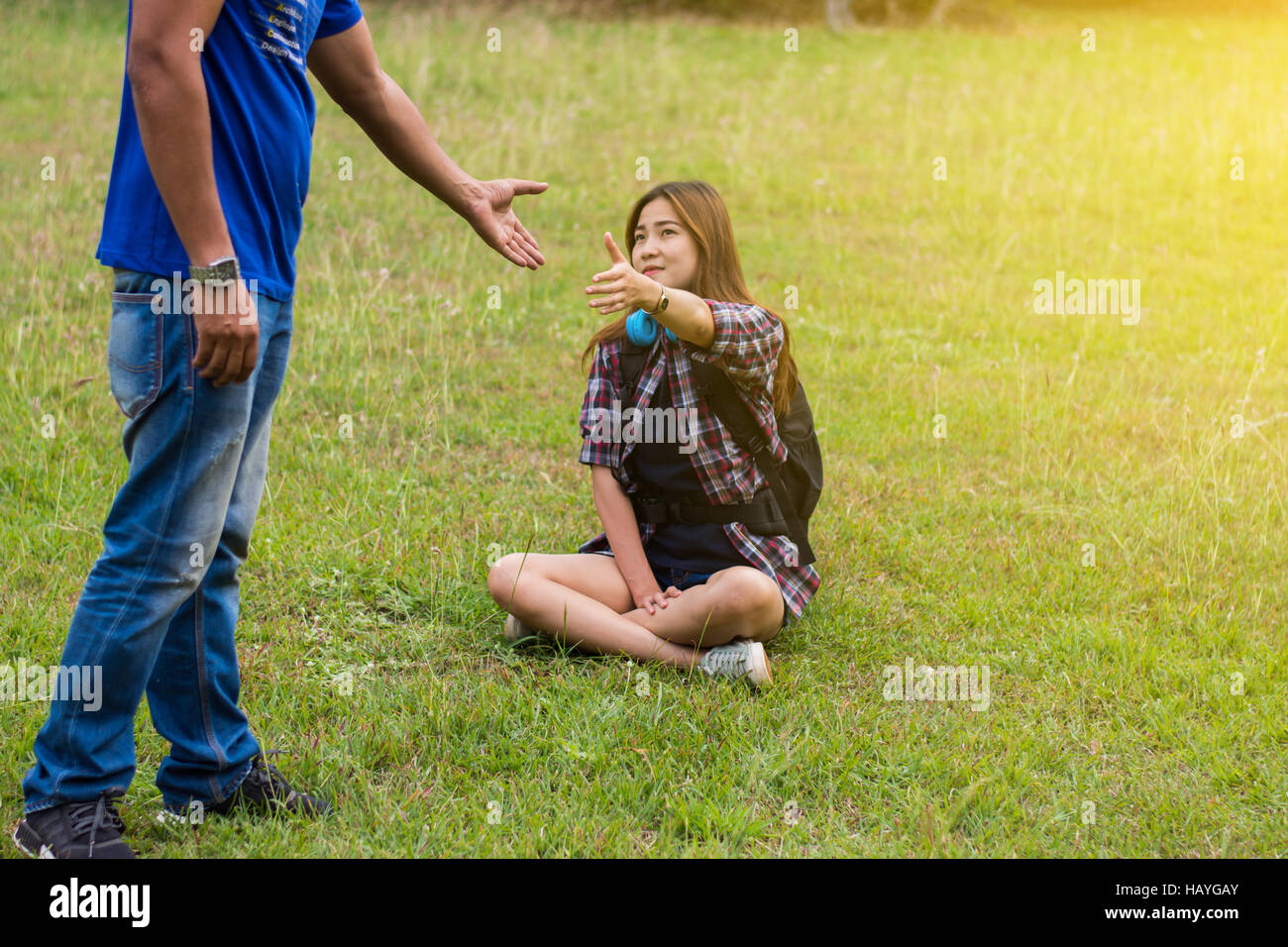 Frau sitzt auf dem Rasen um die Hand des Menschen zu erreichen. Hand und Liebe Konzept zu helfen. Vintage-Ton. Stockfoto