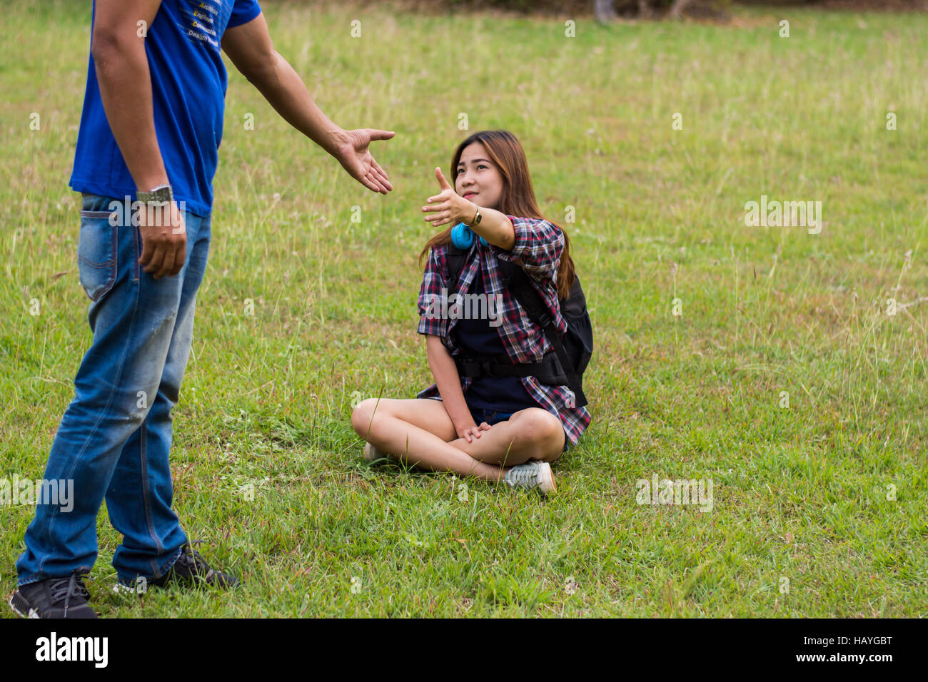 Frau sitzt auf dem Rasen um die Hand des Menschen zu erreichen. Hand und Liebe Konzept zu helfen. Stockfoto
