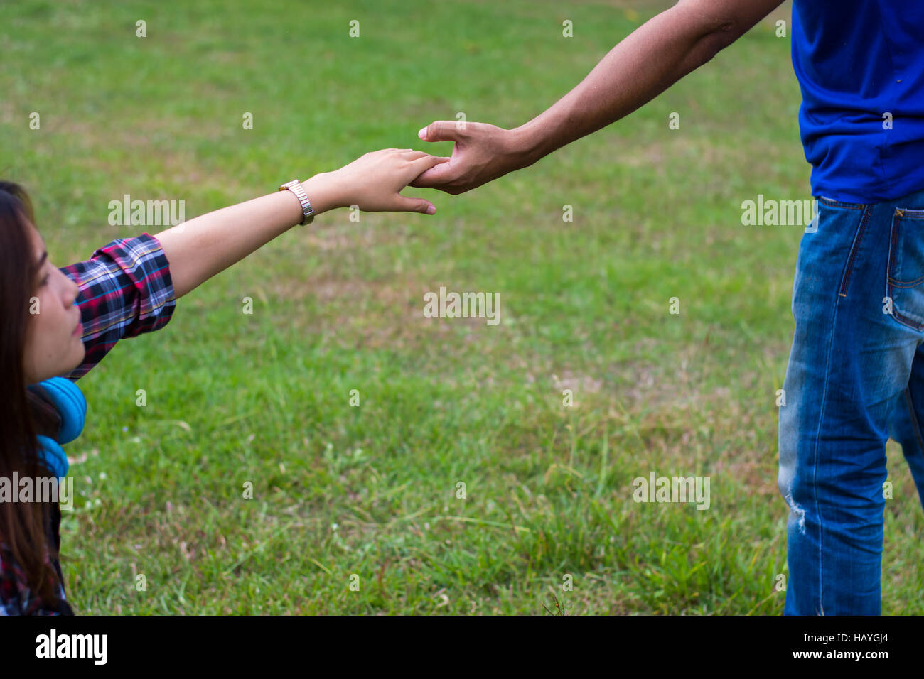 Frau sitzt auf dem Rasen um die Hand des Menschen zu erreichen. Hand und Liebe Konzept zu helfen. Stockfoto