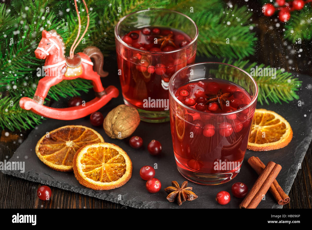 Weihnachten-Cranberry cocktail mit Zimtstangen, Anis Sterne, trockenen Orangenscheiben und Tannenzweigen auf einem schwarzen Stein verziert Stockfoto