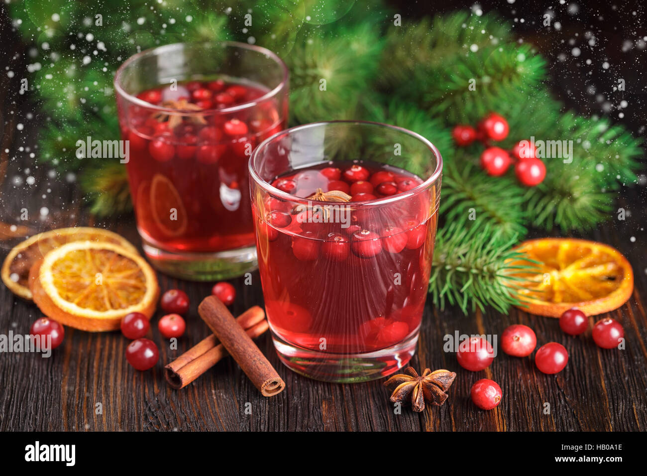 Zwei Gläser Cranberry trinken, Preiselbeeren, Zimtstangen, Anis Sterne und getrocknete Scheiben von Orange auf hölzernen Hintergrund. Stockfoto