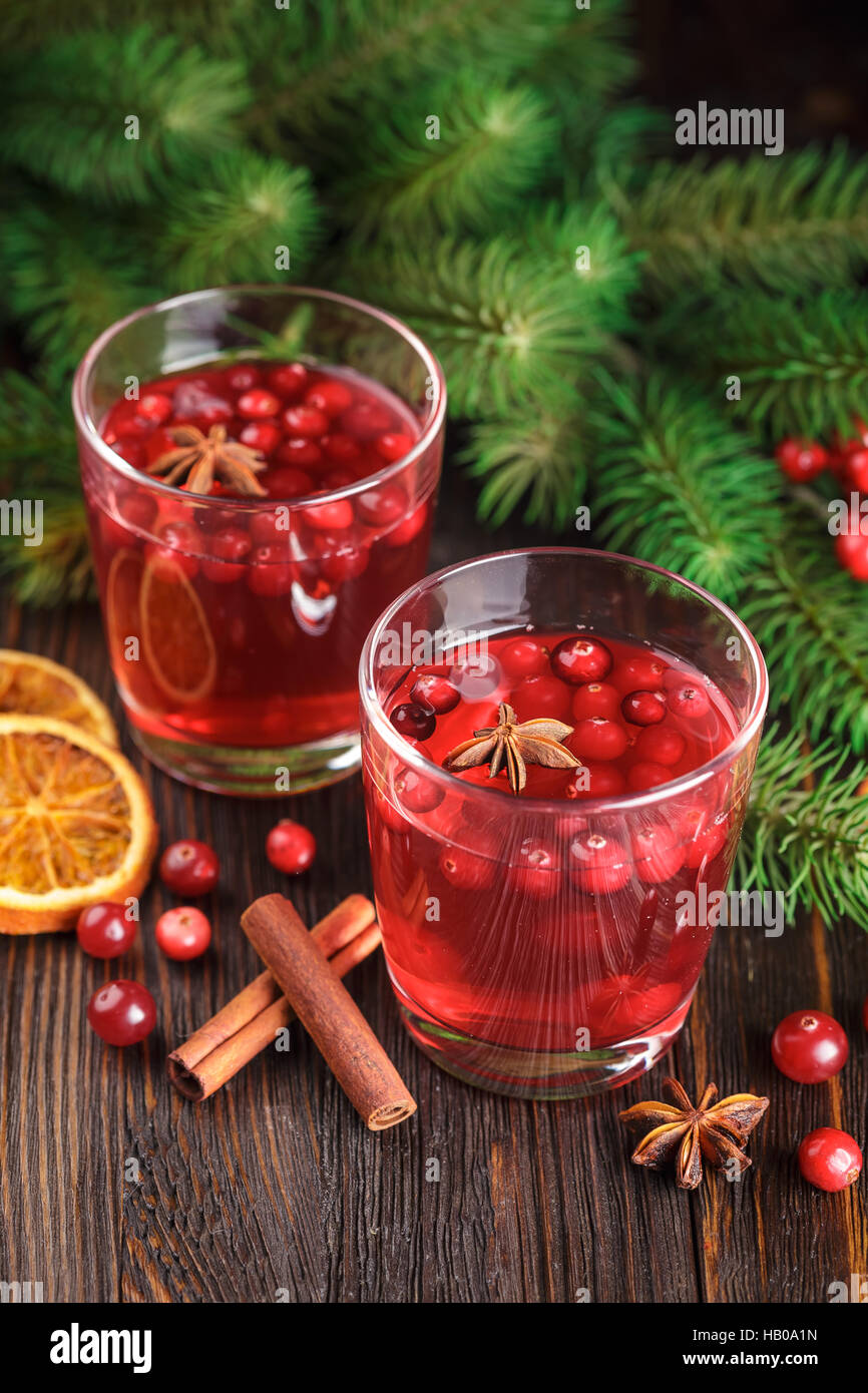 Zwei Gläser Cranberry trinken, Preiselbeeren, Zimtstangen, Anis Sterne und getrocknete Scheiben von Orange auf hölzernen Hintergrund. Stockfoto