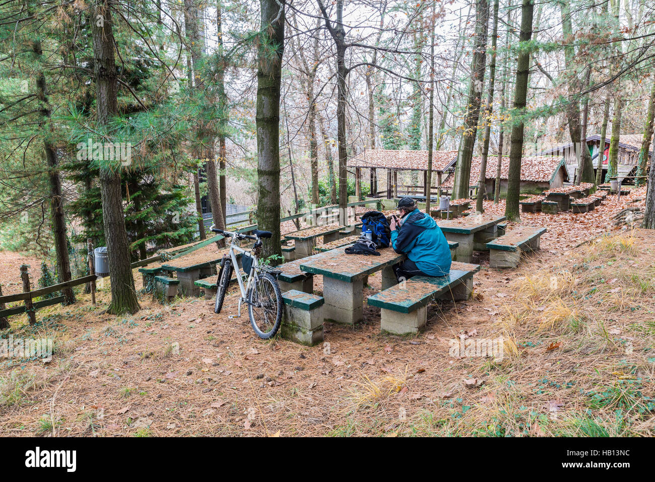 Radfahrer mit Mountainbike und Handy ruht auf dem Picknickplatz Travedona - Monate, Provinz Varese, Italien Stockfoto