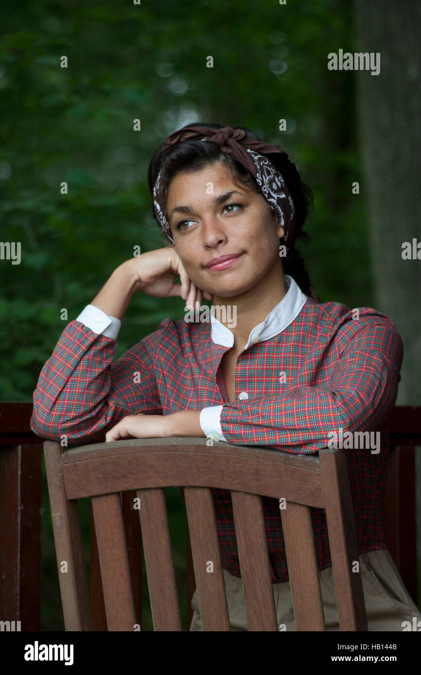 multikulturelle junge Frau im Vintage Kleid stützte sich auf Rückseite des Stuhls Stockfoto