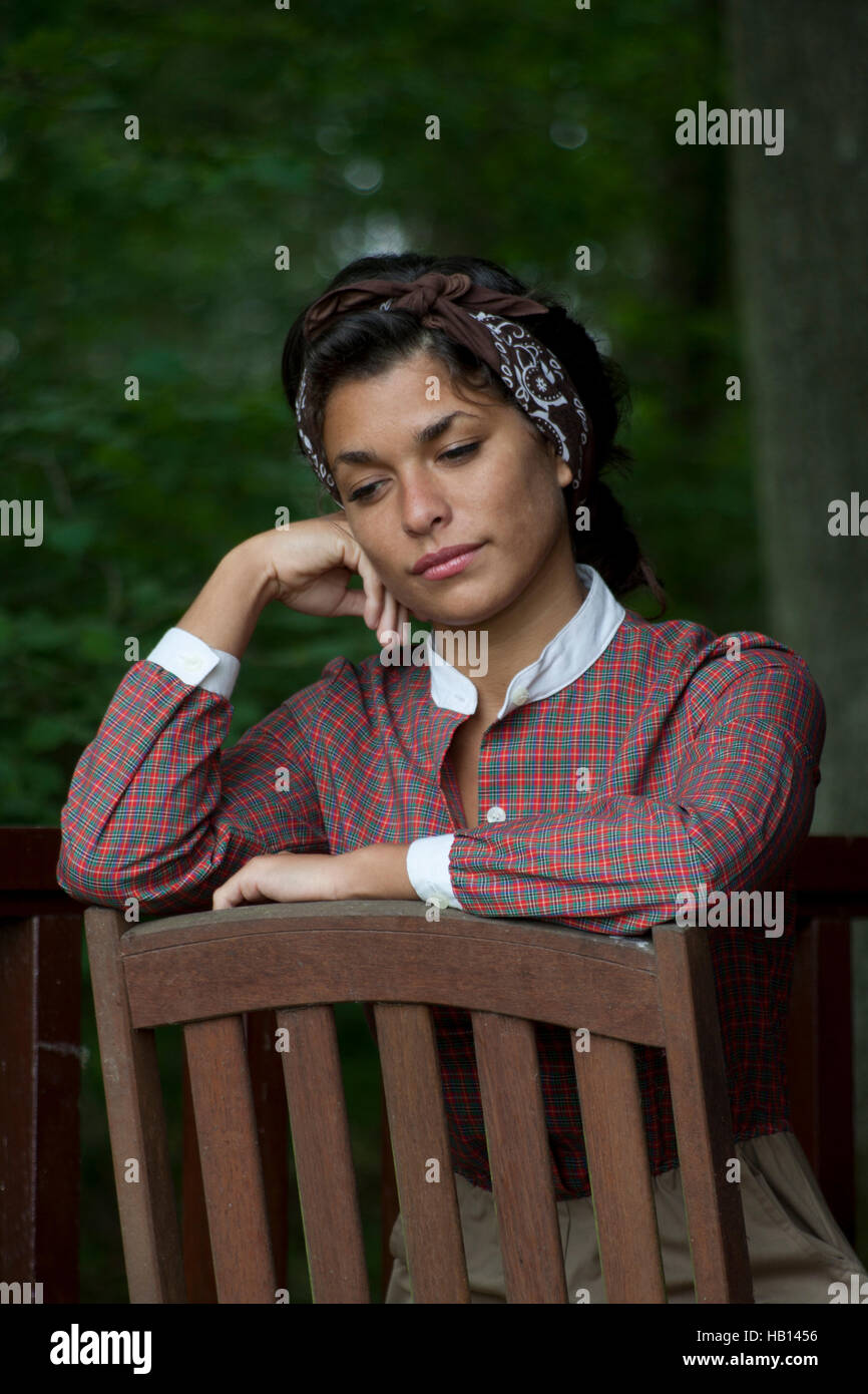 unglücklich multikulturellen junge Frau im Vintage Kleid stützte sich auf Rückseite des Stuhls Stockfoto