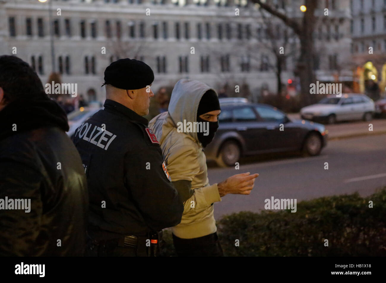 Wien, Österreich. 3. Dezember 2016. Eine vermummte Demonstranten wird Weg von einem Polizeibeamten. Rund hundert Demonstranten marschierten durch Wien einen Tag vor den österreichischen Präsidentschaftswahlen, protestieren gegen den rechtsextremen Kandidaten für die Wahl, Norbert Hofer. Stockfoto