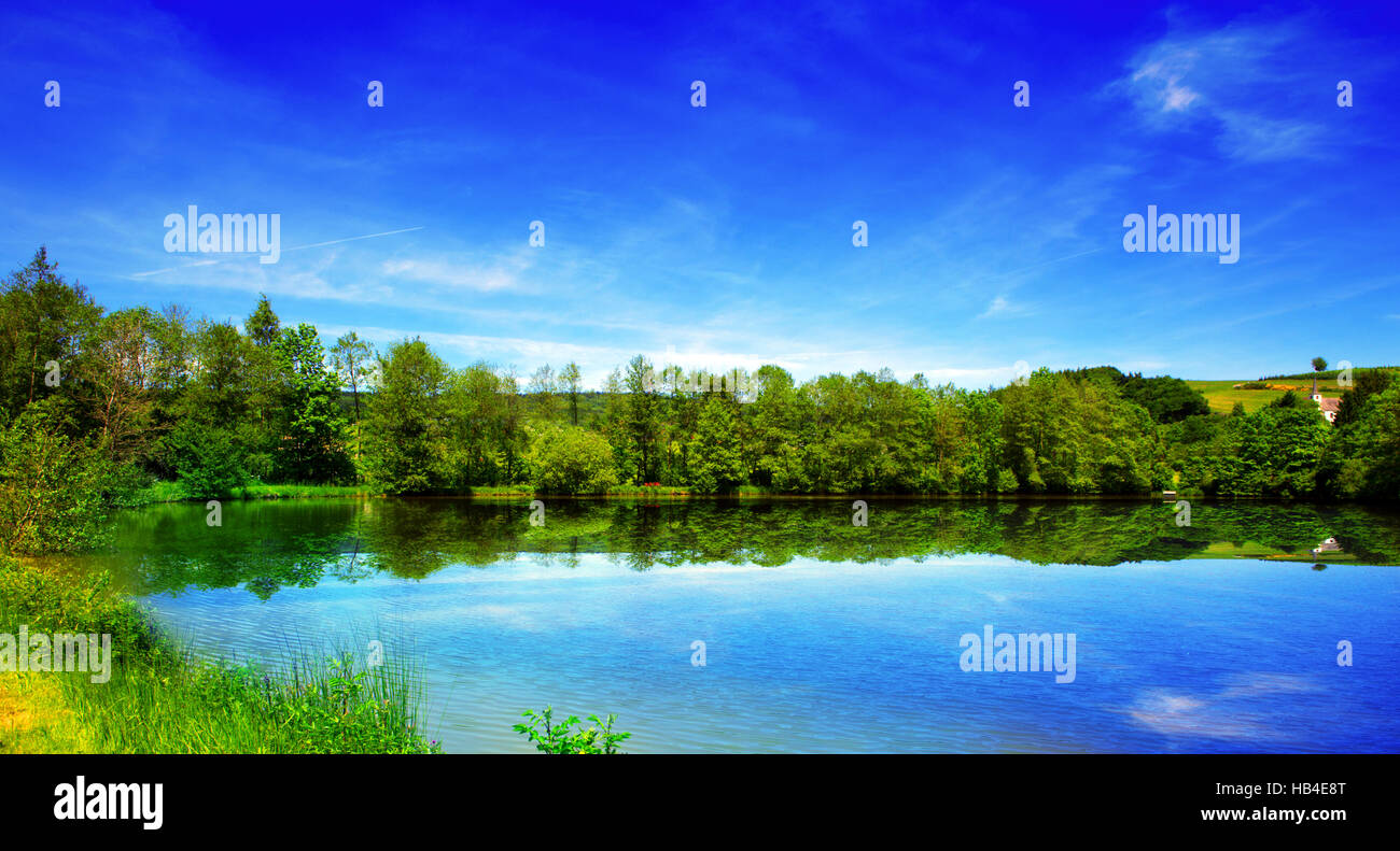 See und grüne Bäume auf Himmelshintergrund. Stockfoto