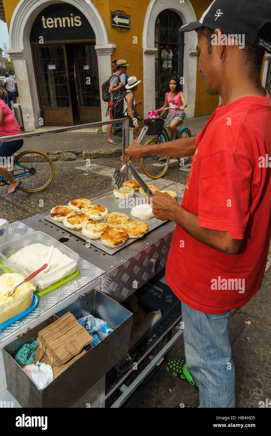 Mann in einem roten T-shirt Verkauf Kartoffelpuffer von einem am Straßenrand Karren, Cartagena, Kolumbien Stockfoto