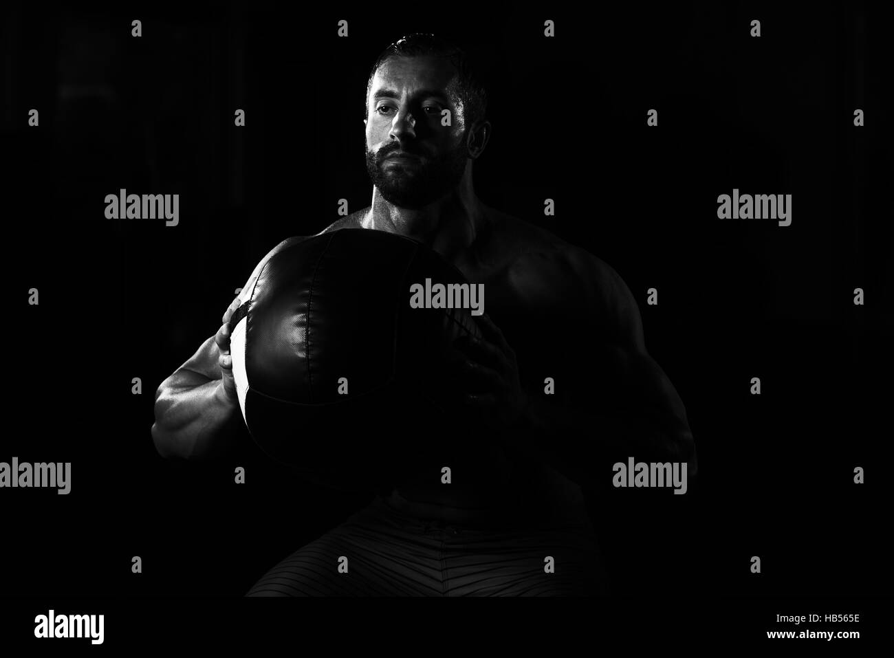 Lateinischen männlichen Athleten kauerte Wand Kugeln Übungen im Fitnessstudio Stockfoto