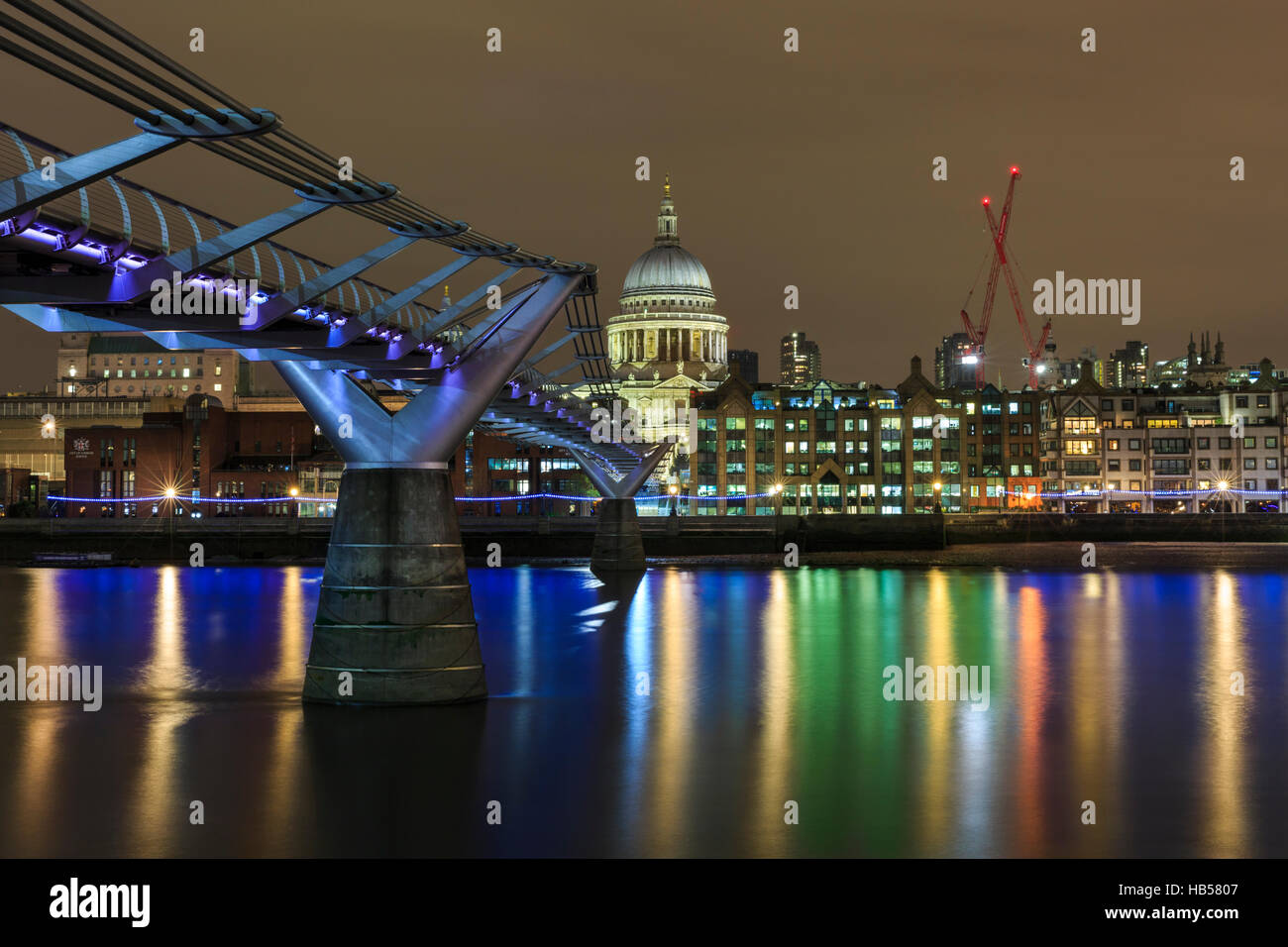 Millennium Bridge und St. Pauls Cathedral beleuchtet in der Nacht mit Reflexionen in der Themse Stockfoto