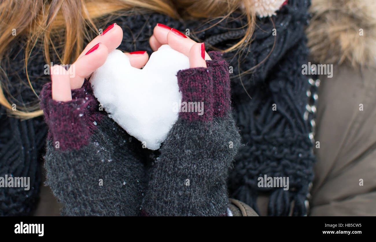 Frau Hände halten Herz geformten Schneeball im freien Stockfoto