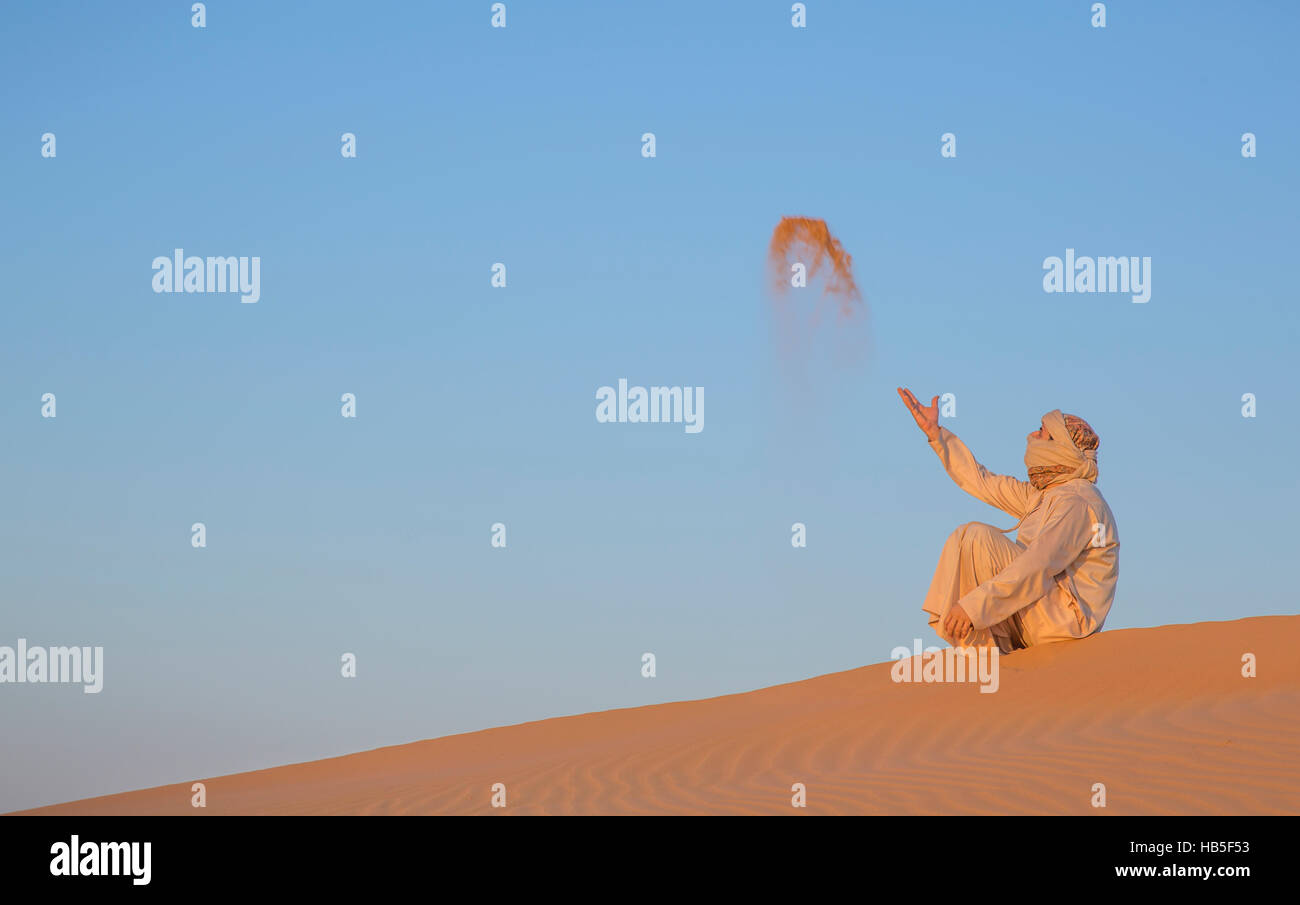 Mann in traditioneller Kleidung in einer Wüste bei Sonnenaufgang in der Nähe von Dubai Stockfoto