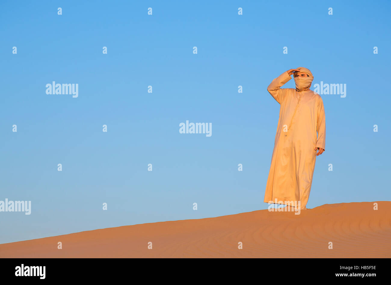 Mann in traditioneller Kleidung in einer Wüste bei Sonnenaufgang in der Nähe von Dubai Stockfoto